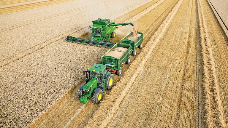 John Deere S-seriens sk&ouml;rdetr&ouml;skor t&ouml;mmer vete i dubbla vagnar som dras av en traktor