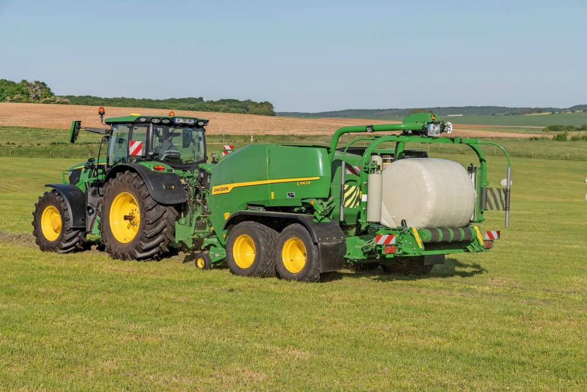 John Deere C442R-inplastarpress dragen av en John Deere 6R 185 som pressar ensilagebalar med hög täthet