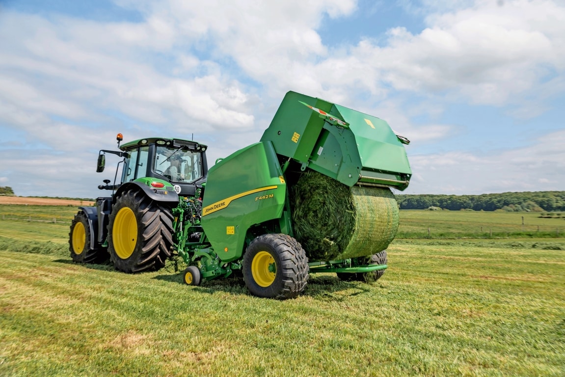John Deere F442M-balpress dragen av en John Deere 6M-traktor som matar ut en gräsbal