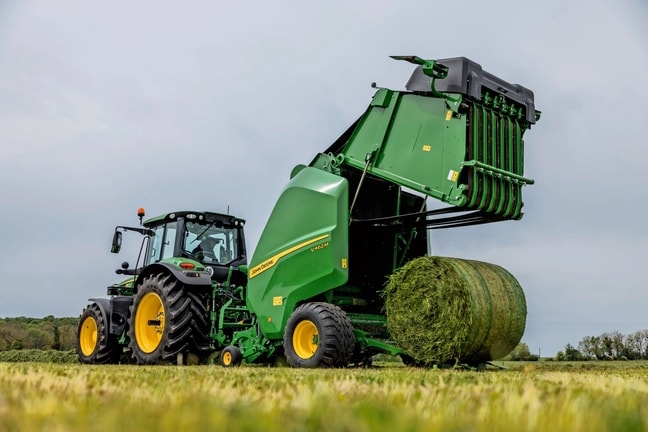 John Deere V462M-balpress dragen av en John Deere 6M-traktor som matar ut en gräsbal