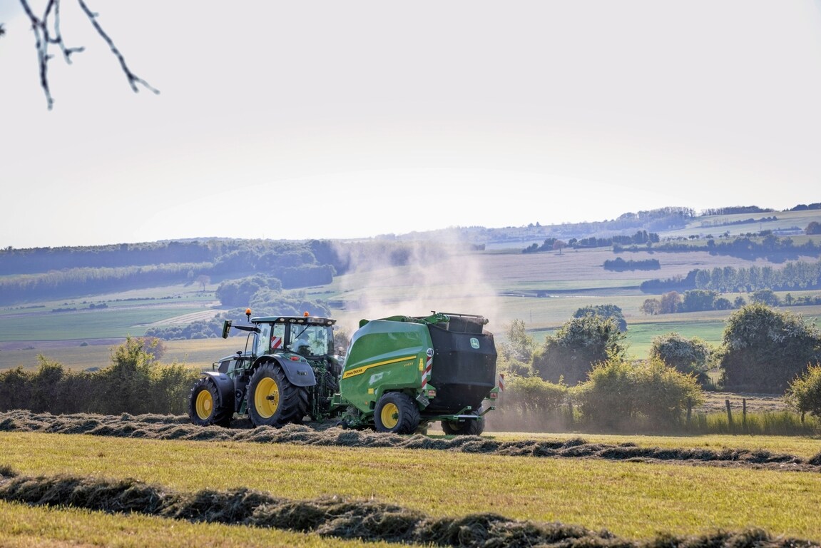 John Deere V462R dragen av en John Deere 6R 185-traktor som pressar hö