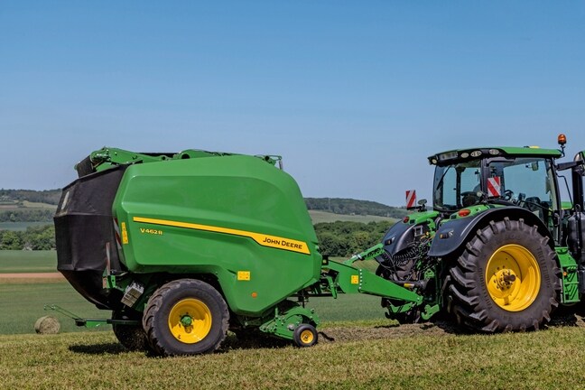 John Deere V462R dragen av en John Deere 6R 185-traktor som pressar hö